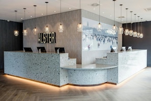 A reception area with a speckled granite counter, pendant lighting, and a large wall mural. - Motel One Hamburg-Alster (Hamburg)