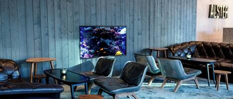 Ein modernes Wohnzimmer mit einem großen Flachbildfernseher, Ledersofas und Holztischen.