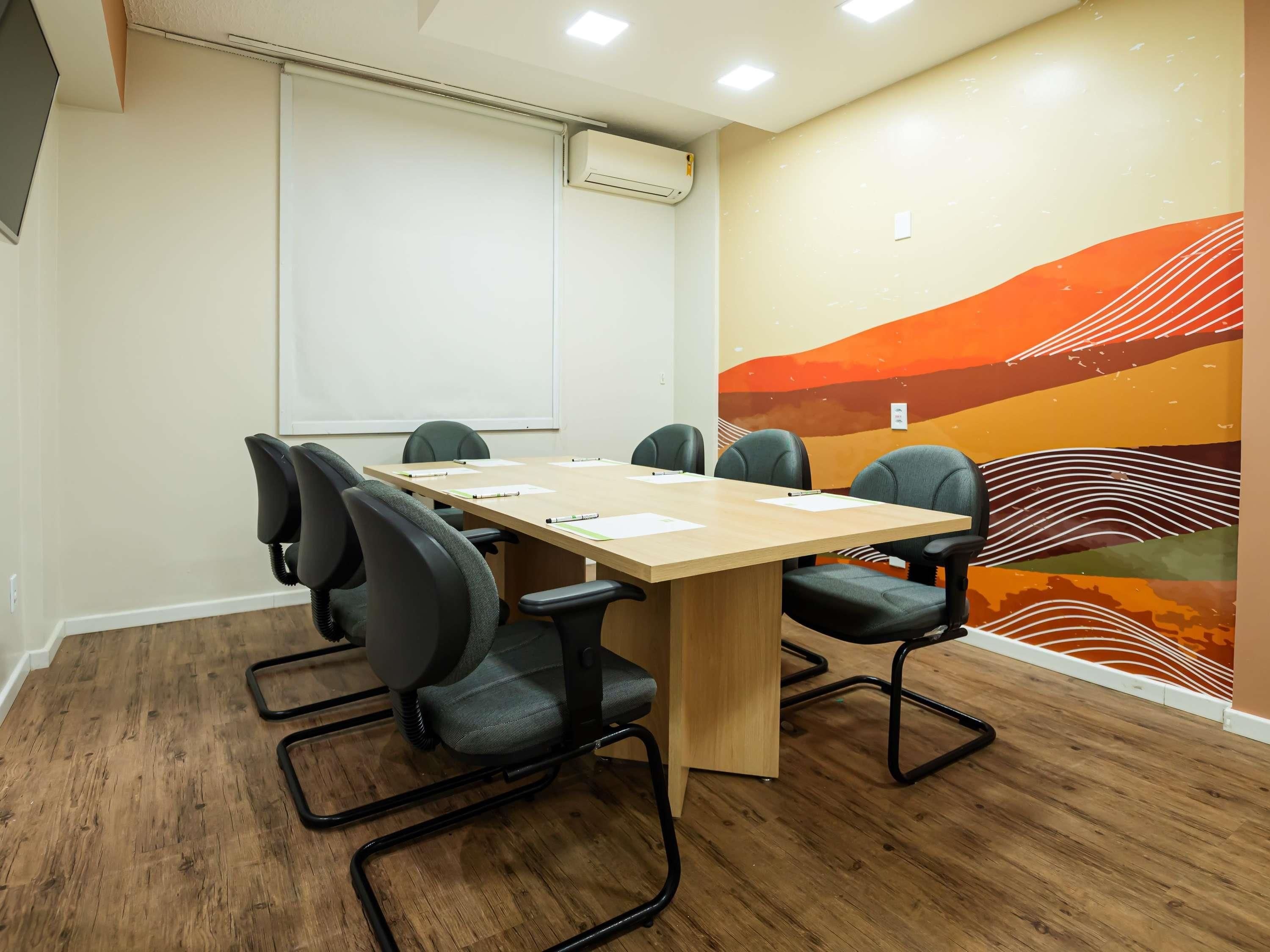 Une salle de conférence équipée d’une table en bois, de six chaises, d’un tableau blanc et d’un appareil de climatisation.