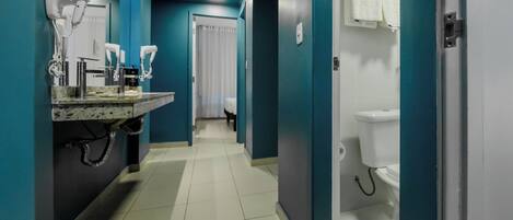 Un baño moderno con lavamanos, secadores de pelo y un inodoro.
