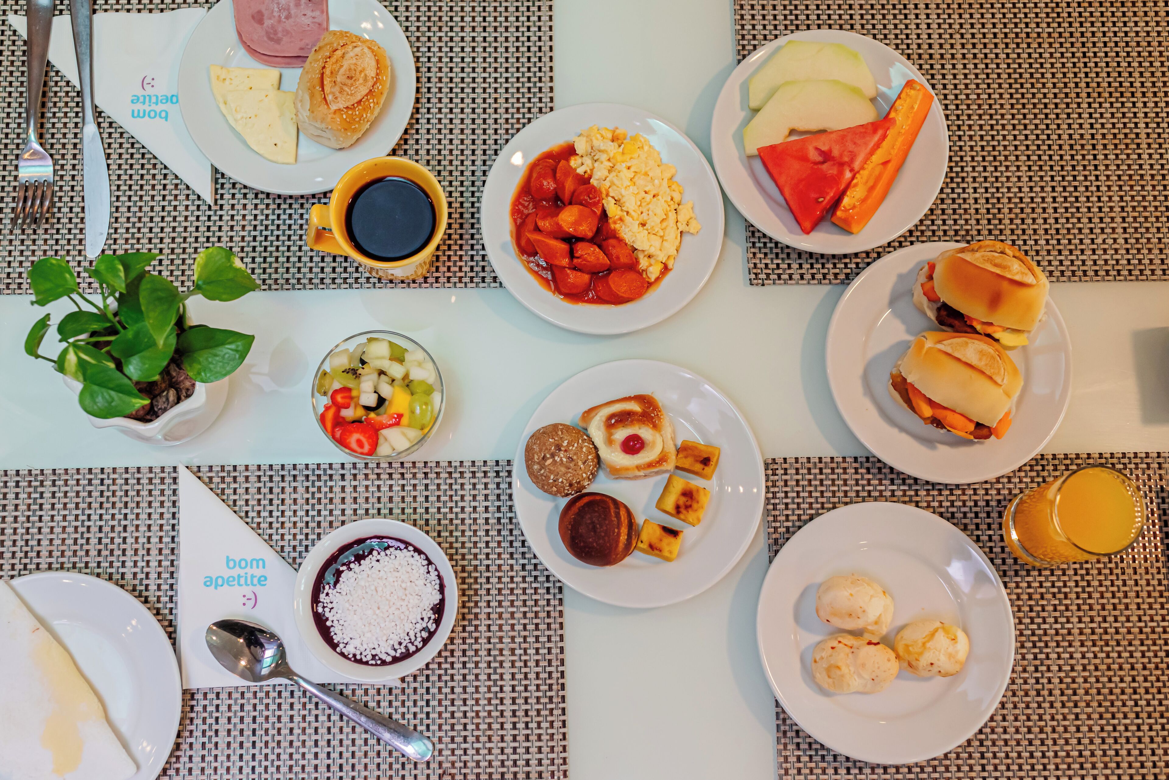 A breakfast buffet with various dishes including eggs, sausages, and pastries.