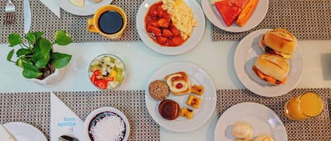 A breakfast buffet with various dishes including eggs, sausages, and pastries.