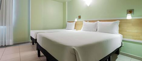 Una habitación de hotel con una cama grande, un cabecero de madera y una ventana con cortinas.