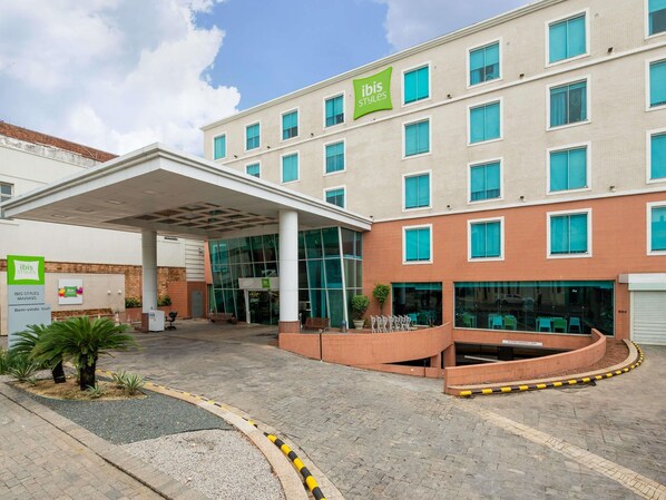 A hotel with a modern design, featuring a covered entrance, multiple windows, and a sign for 'ibis Styles.'