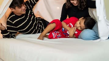 Una cama con dosel blanco, una persona vestida a rayas y un niño con camisa roja.