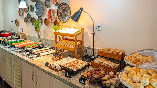 A buffet with various food items, a wall with decorative plates, and a lamp. - ibis Styles Manaus (Manaus)