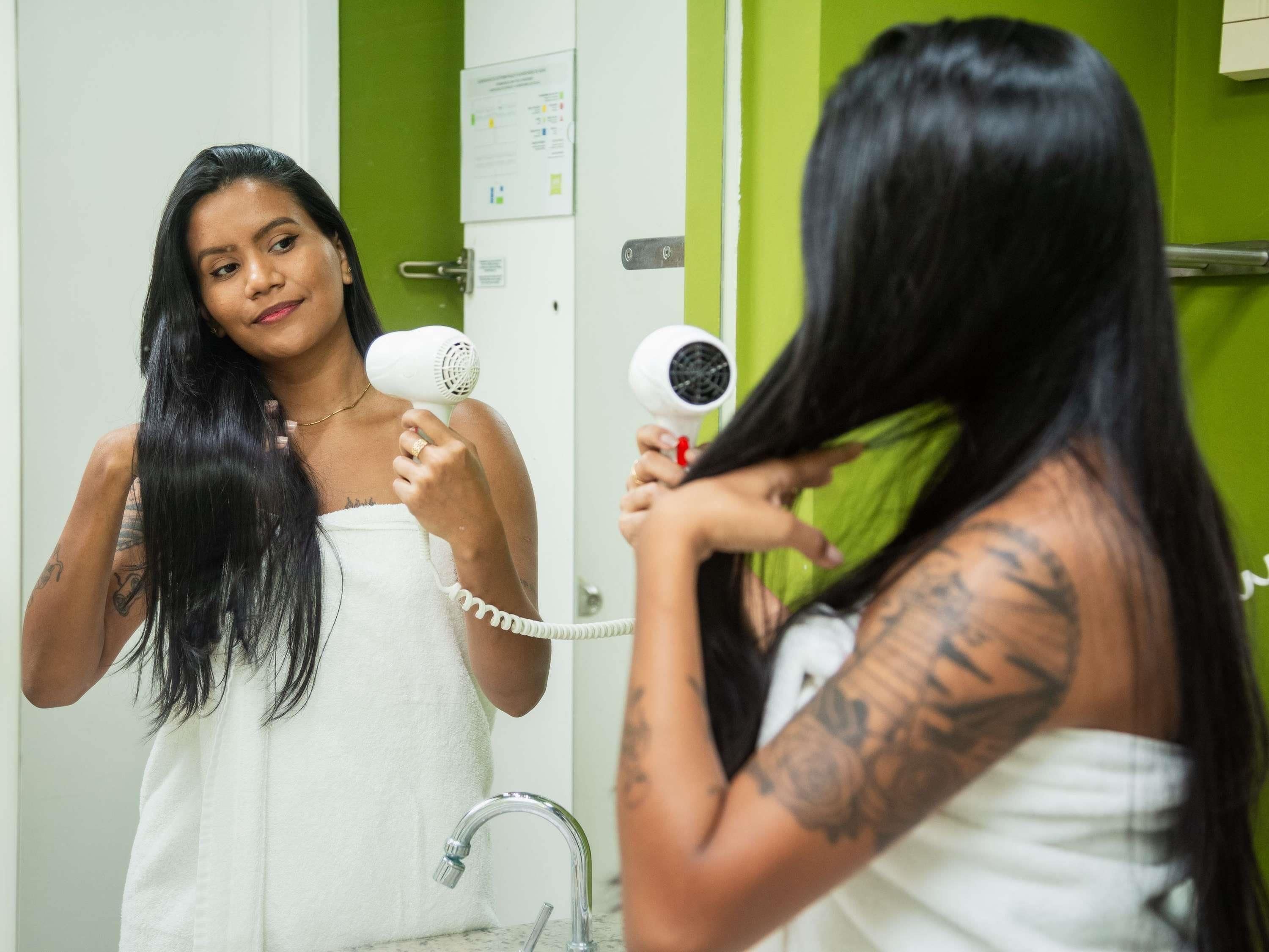 Un baño con pared verde, una toalla blanca y un secador de pelo.