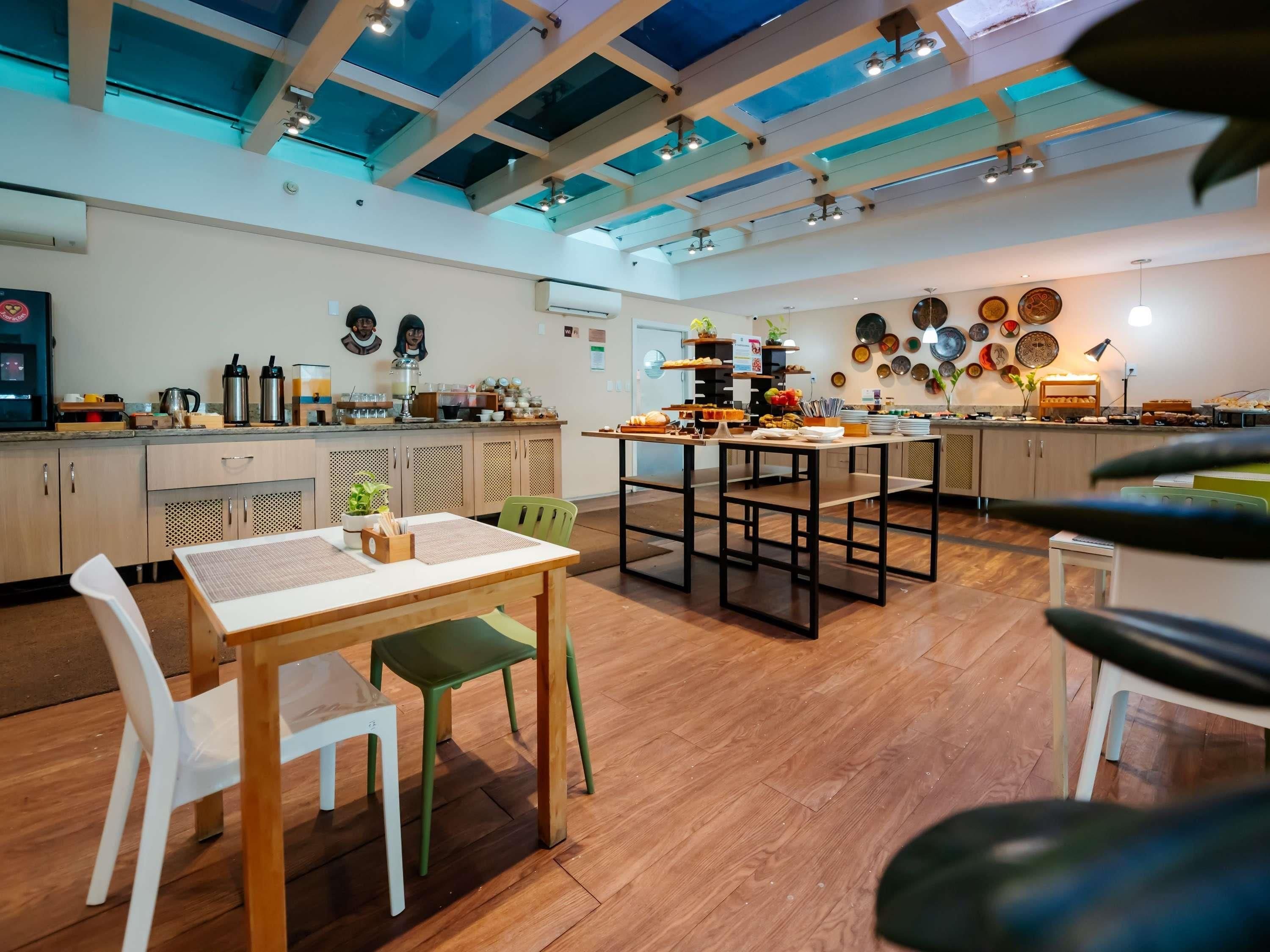 A modern kitchen with wooden cabinets, a dining area with a table and chairs, and a ceiling with skylights.