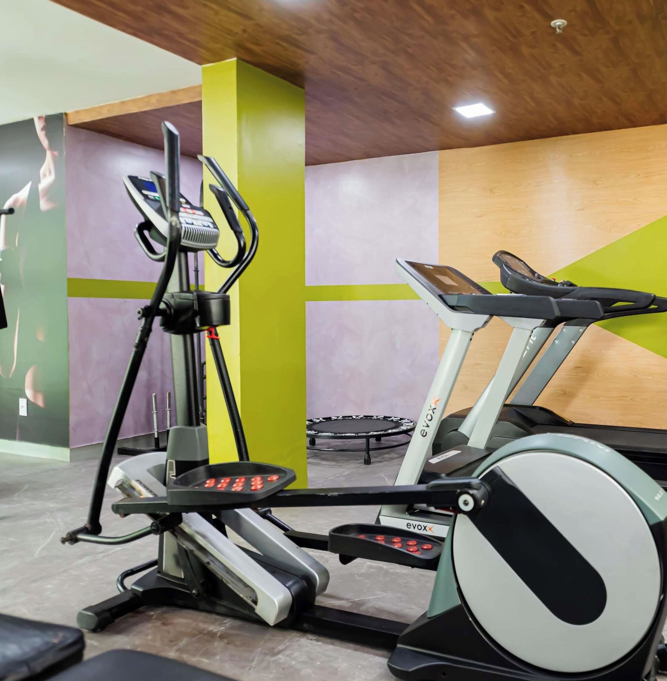 A gym with stationary bikes, a treadmill, and a mirror.