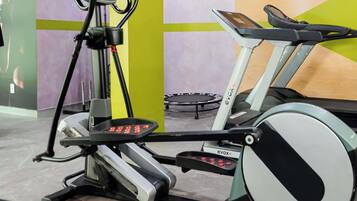 A gym with stationary bikes, a treadmill, and a mirror.