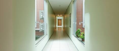 A long, narrow hallway with a tiled floor and large windows on both sides.