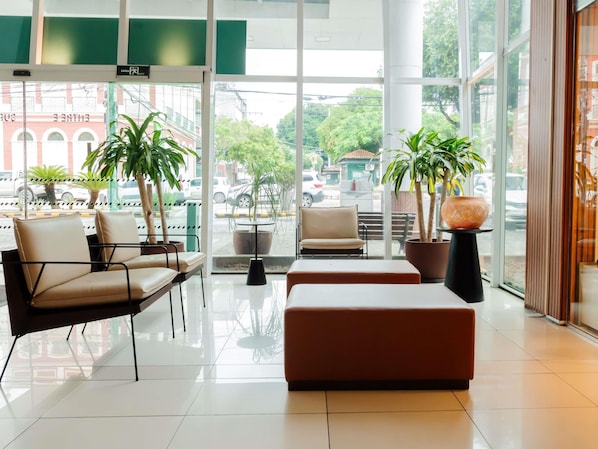 Un vestíbulo moderno con asientos, ventanas amplias y plantas en macetas.