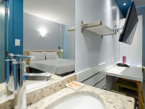A hotel room with a bed, a desk, a mirror, a TV, and a bathroom with a sink and toilet. - ibis Styles Manaus (Manaus)