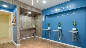 A room with a blue wall labeled "PASSADORIA," wooden flooring, and two ironing stations with electric irons. - ibis Styles Manaus (Manaus)