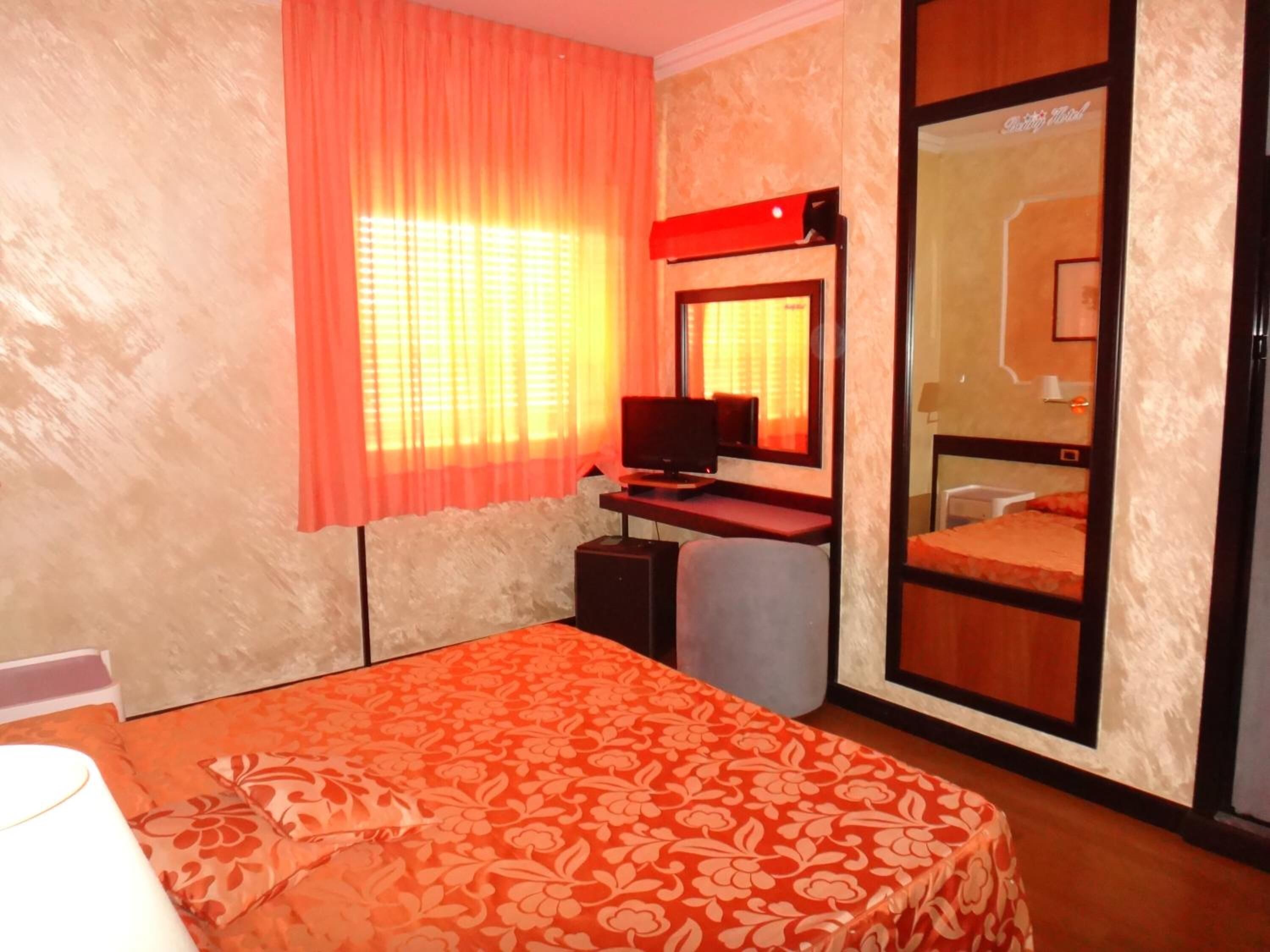 A hotel room with a bed, a desk, a TV, and a wardrobe.