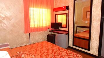 A hotel room with a bed, a desk, a TV, and a wardrobe.