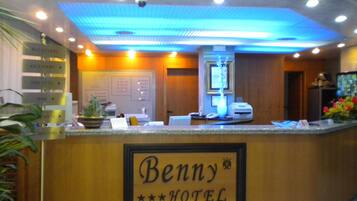 A reception desk at Benny Hotel with directional signs for amenities like the reception, bathroom, bar, and meeting rooms.