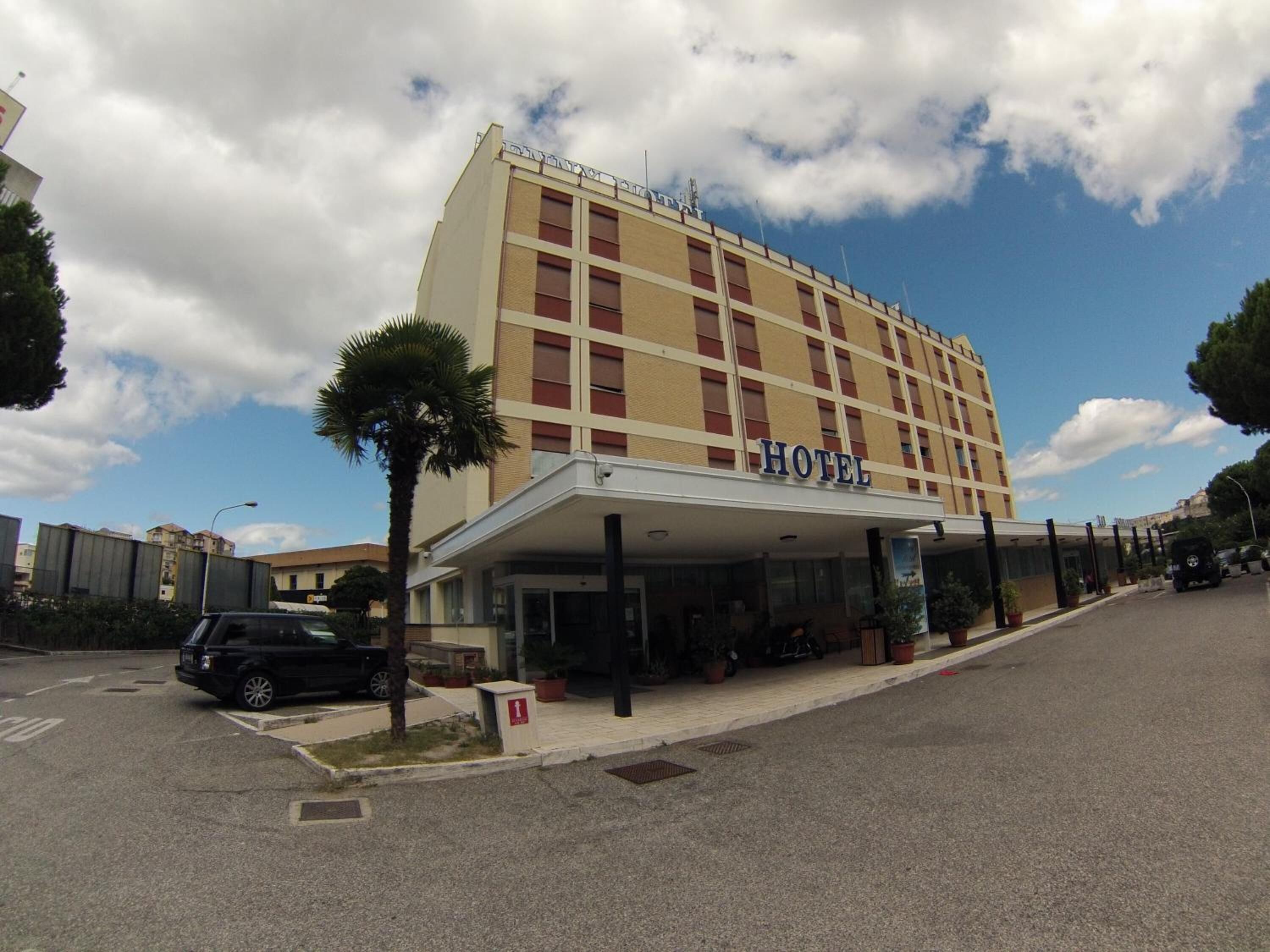 A hotel with a flat facade, multiple windows, and a covered entrance.