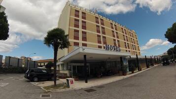 A hotel with a flat facade, multiple windows, and a covered entrance.