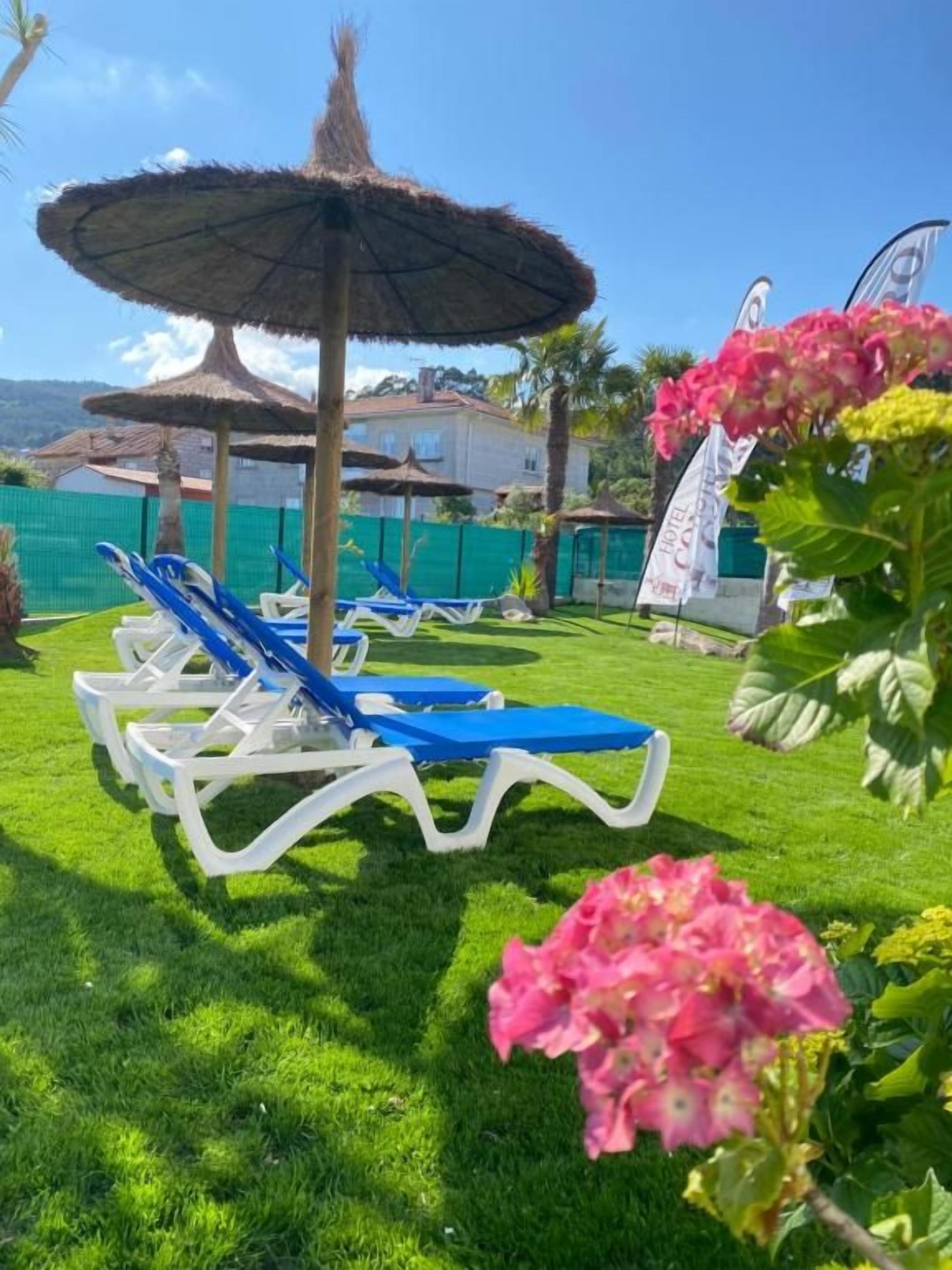Un área junto a la piscina con sillones de descanso y sombrillas.
