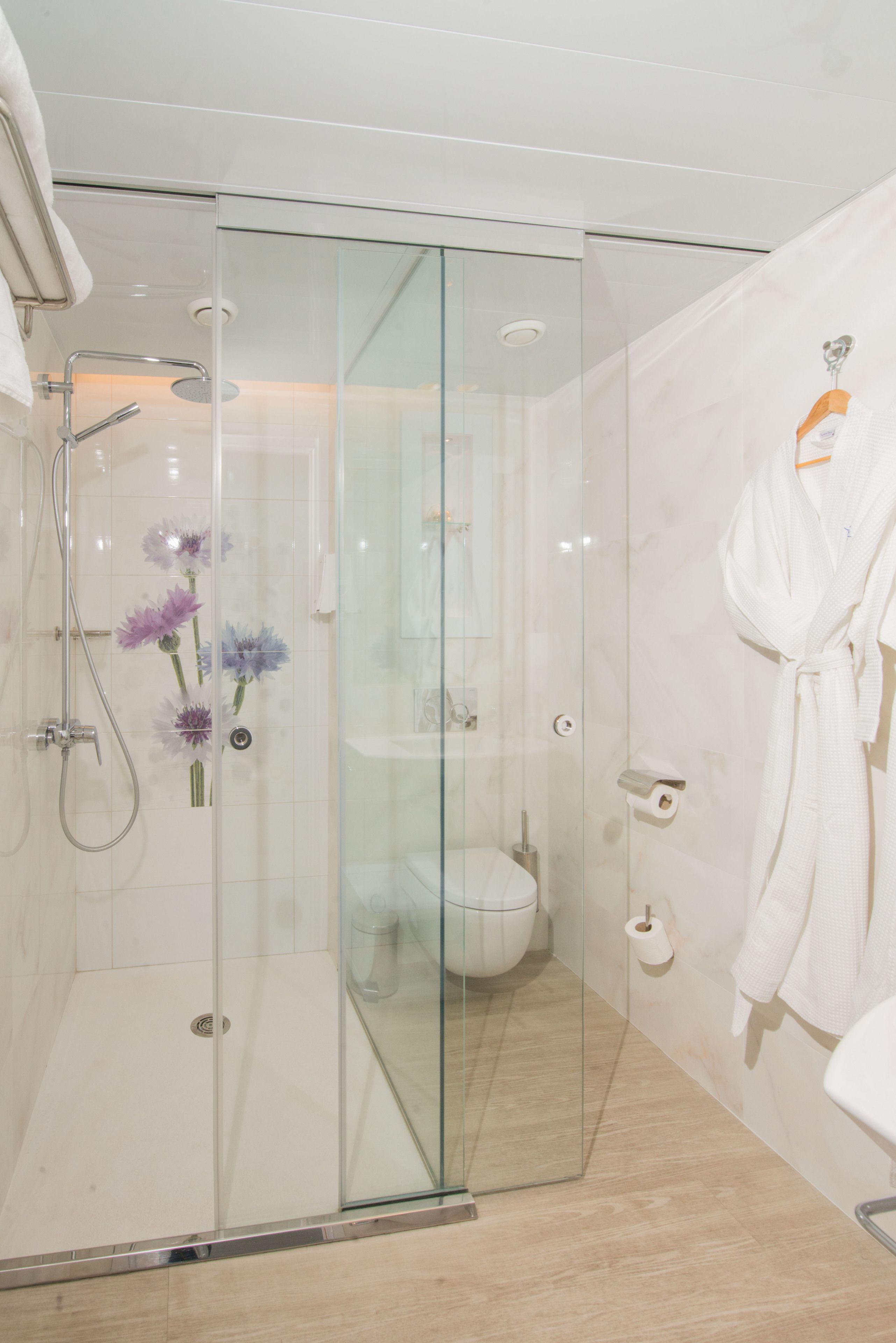 A modern bathroom with a glass shower enclosure, a white toilet, and a white bathtub.