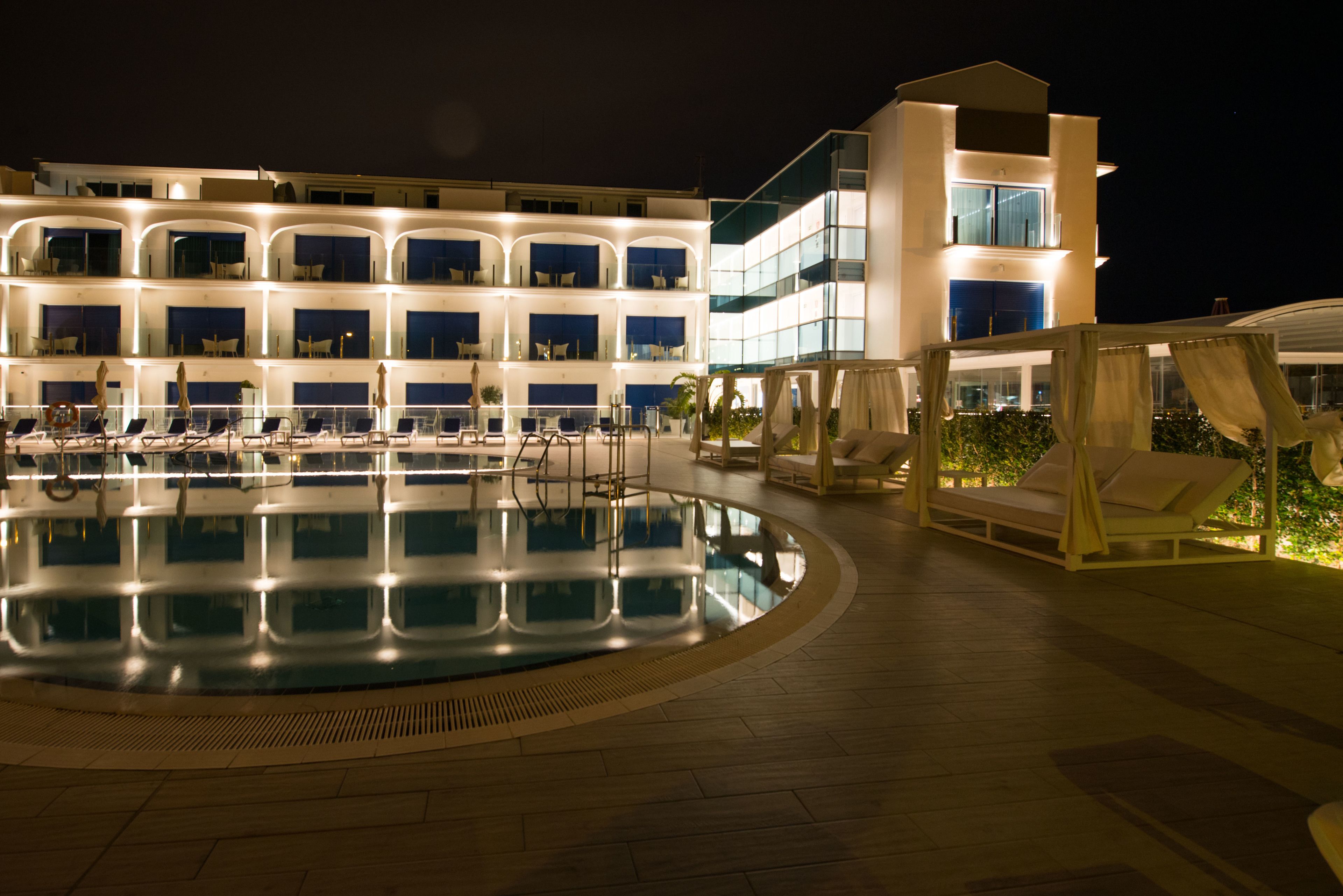 Un hotel con piscina, varios balcones e iluminación exterior.
