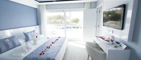 A modern hotel room with a large bed, a desk, a TV, and a view of the outdoors.