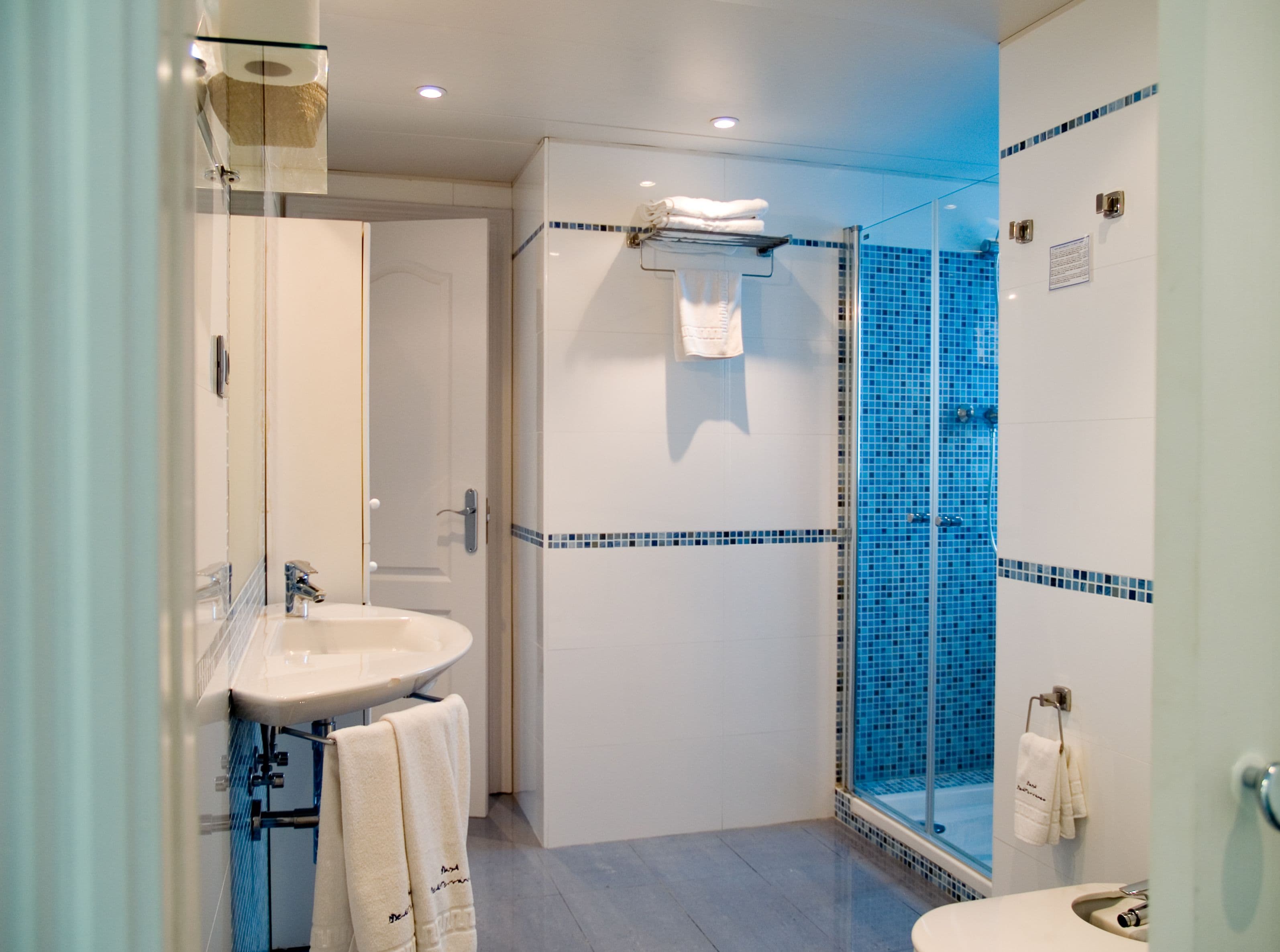 Un baño moderno con cabina de ducha de vidrio, lavamanos y un inodoro.