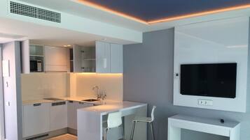 A modern kitchen with integrated appliances, a dining area with a bar stool, and a mounted TV.