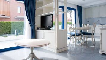 Een moderne keuken met witte kasten, een eettafel met stoelen en een televisie op een dressoir.