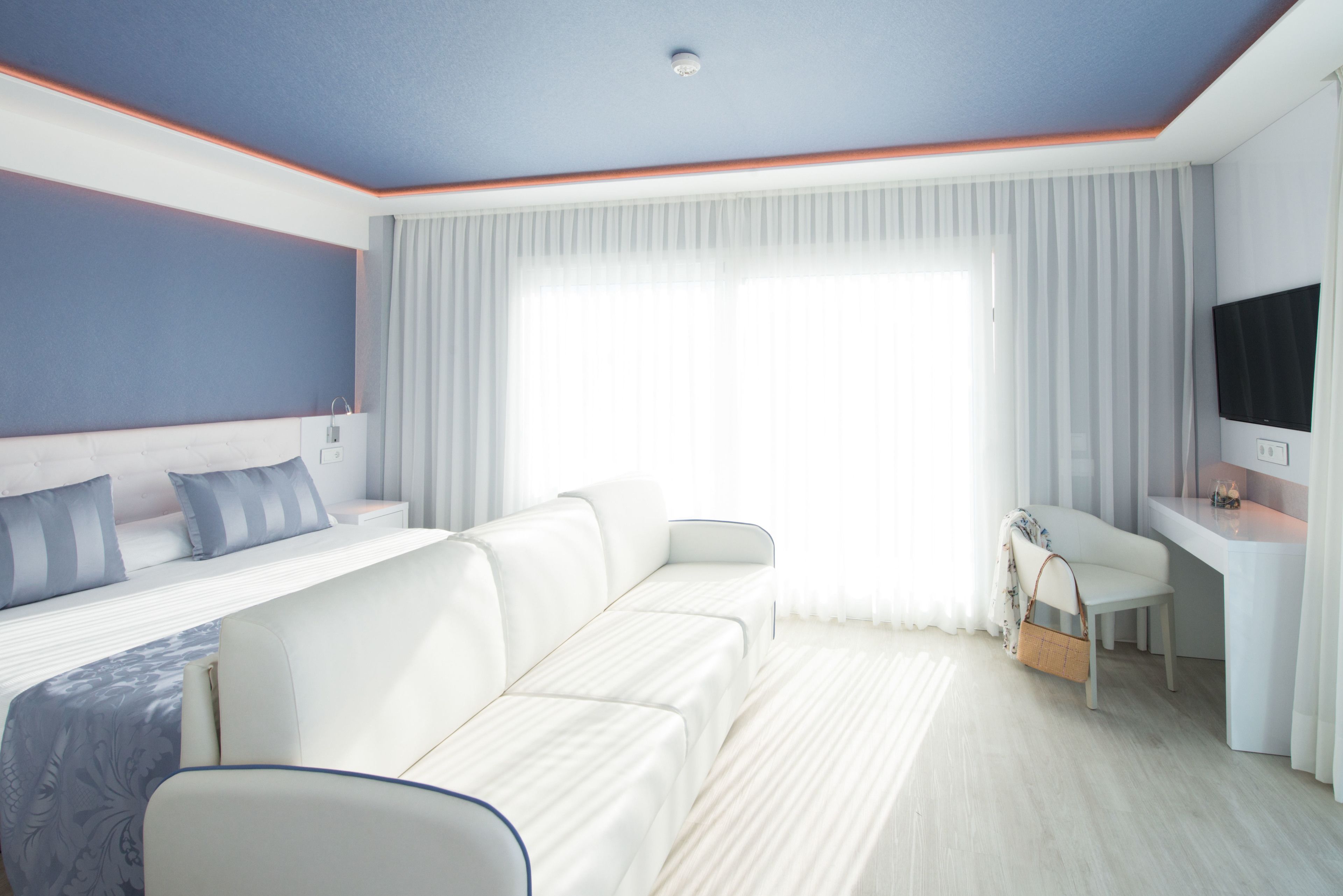 Une chambre d’hôtel moderne équipée d’un lit, d’un canapé, d’un bureau et d’une télévision.