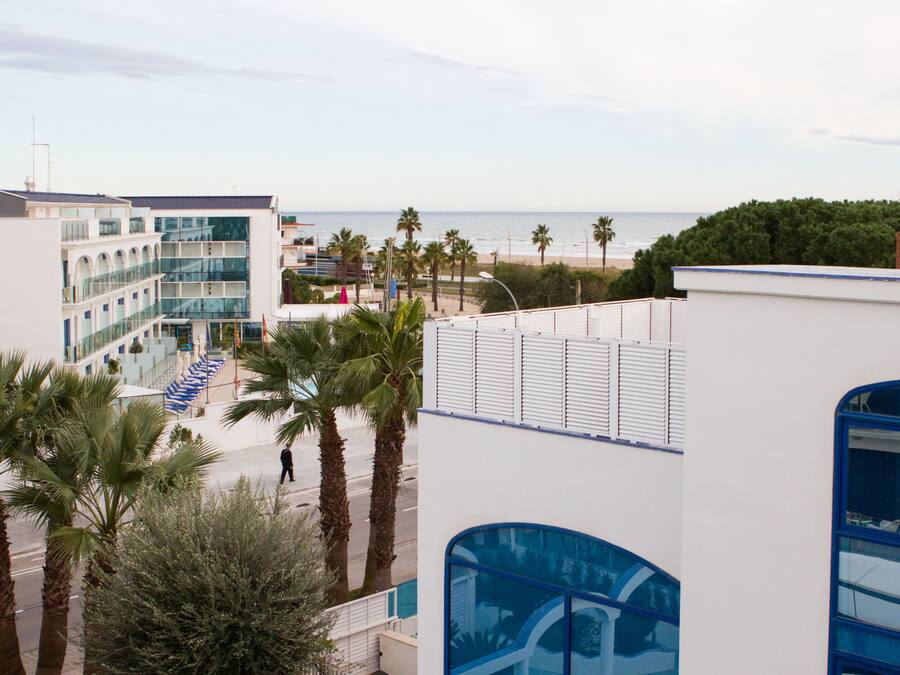 Een kusthotel met een modern architectonisch ontwerp, met een opvallende glazen gevel en uitzicht op het strand.
