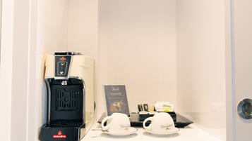A coffee machine, two cups, and a sign in a hotel room.