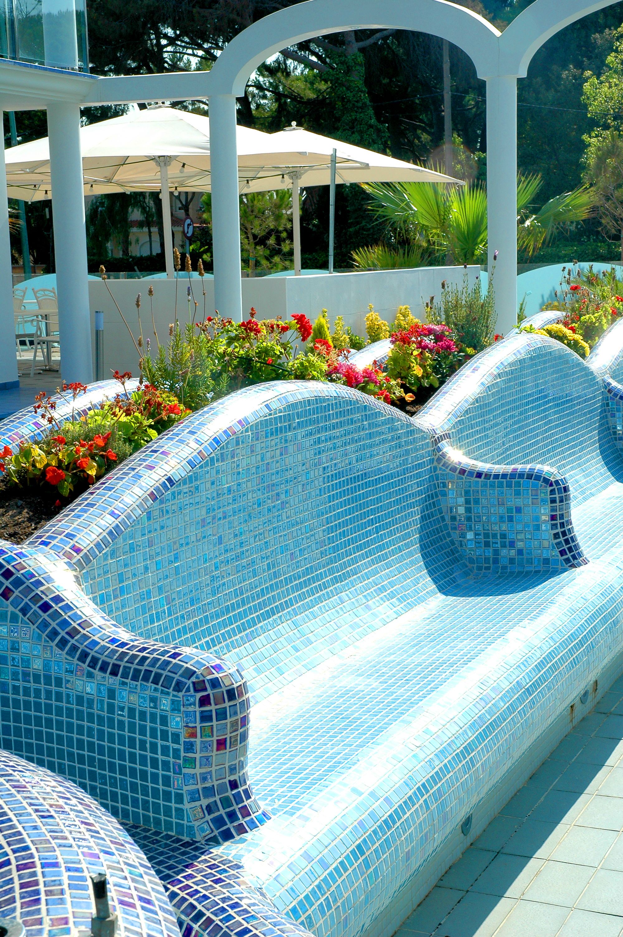 Une piscine aux carreaux de mosaïque bleus et aux colonnes blanches.