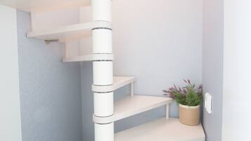 A corner of a room with a white spiral staircase, a small potted plant, and a light blue wall.