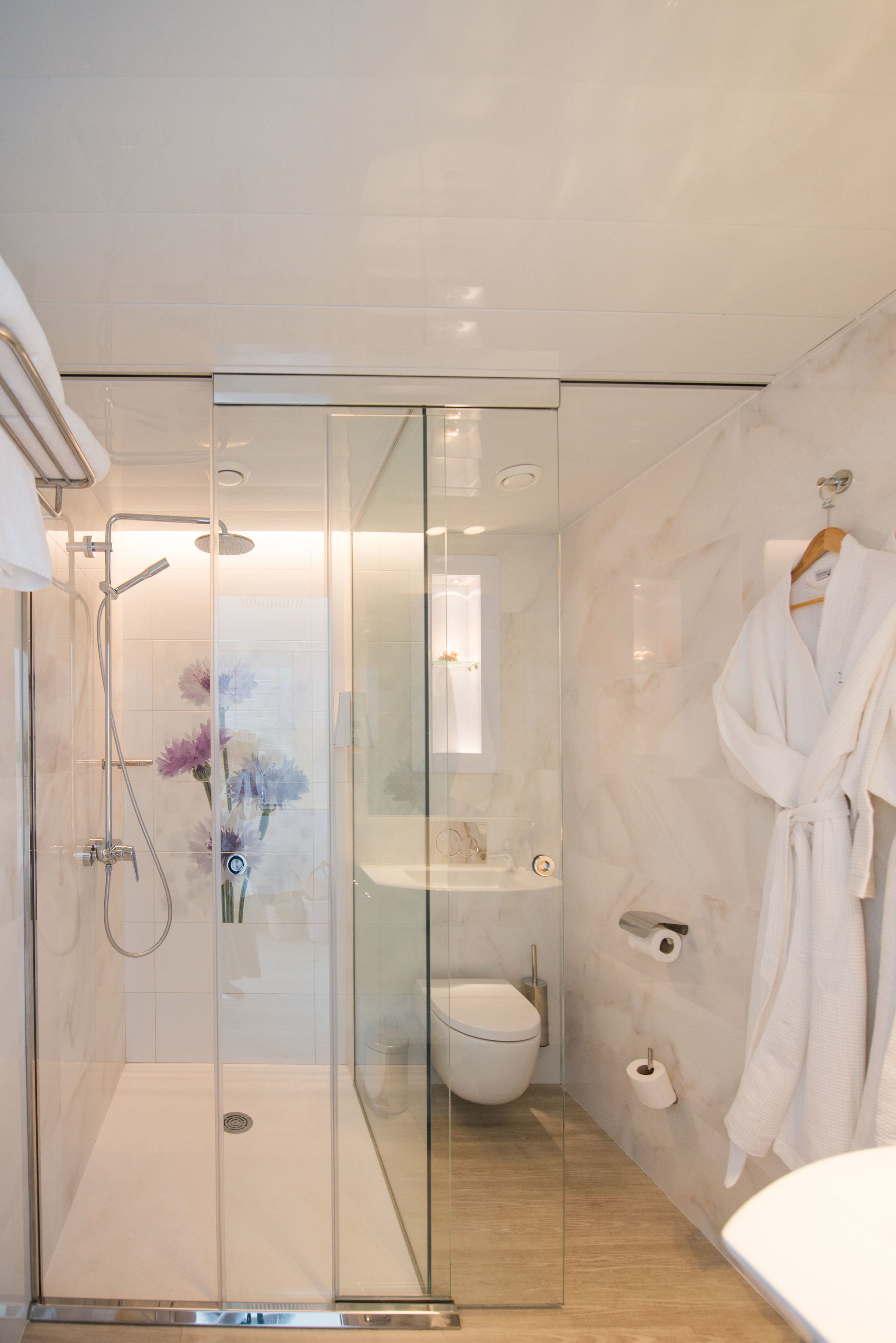 Une salle de bain moderne dotée d’une douche à parois de verre, de toilettes et d’un lavabo.