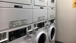 A row of stacked laundry machines with operating instructions and digital displays. - Drummond Apartments Services (Carlton)