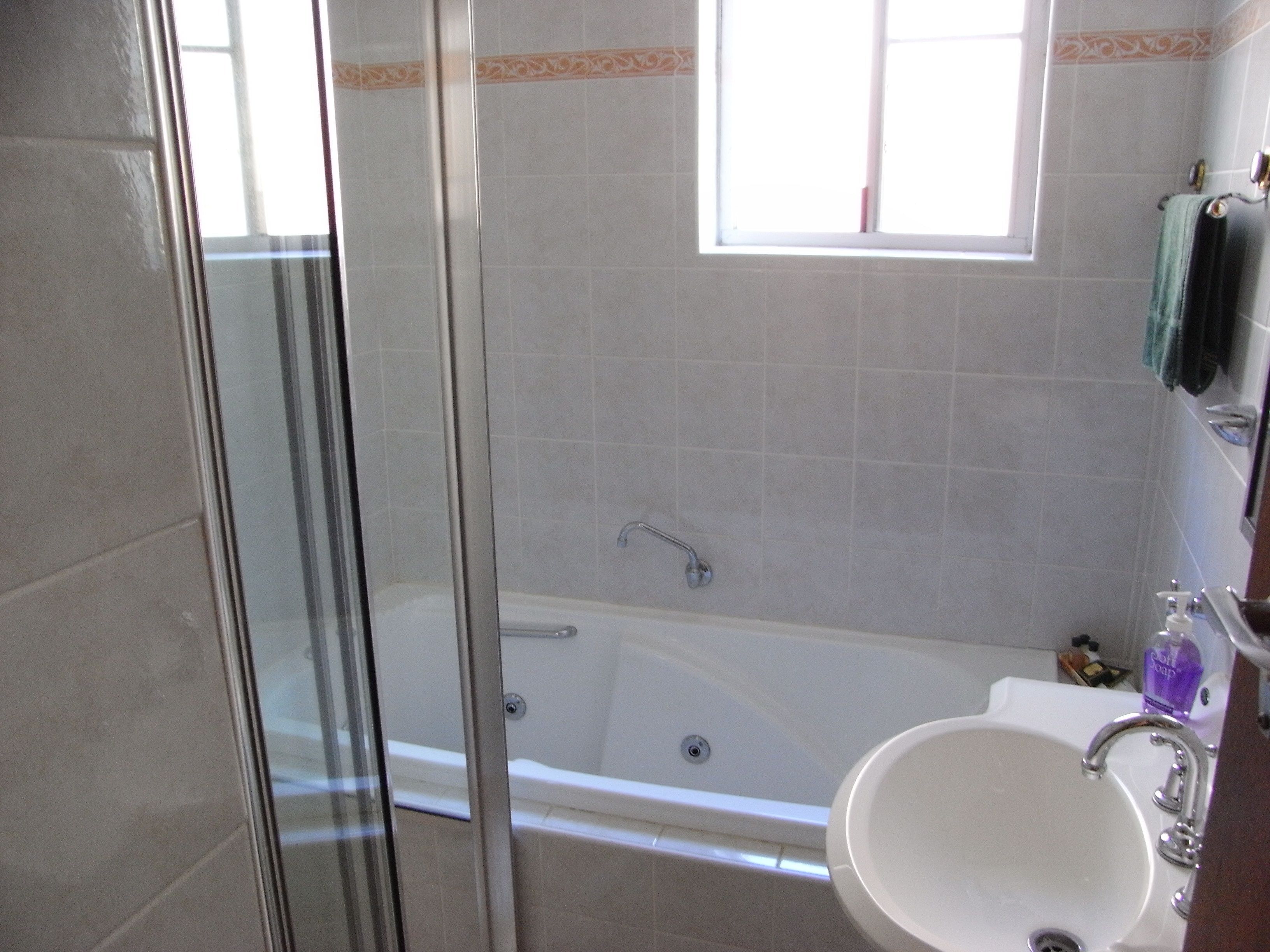 A bathroom with a glass-enclosed shower, a bathtub, and a sink with a faucet.