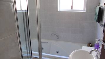 A bathroom with a glass-enclosed shower, a bathtub, and a sink with a faucet.