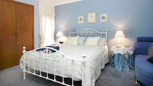A bedroom with a bed, two bedside tables, a wardrobe, and a blue armchair. - Lavender House B&B (The Entrance)