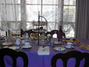 A dining table set with multiple plates, cups, and a tiered serving stand.