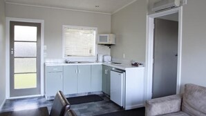 A compact kitchen with grey cabinets, a microwave, and a dishwasher. There is a dining area with a table and chairs.