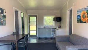 A compact living space with a dining area, kitchenette, and a gray sofa.