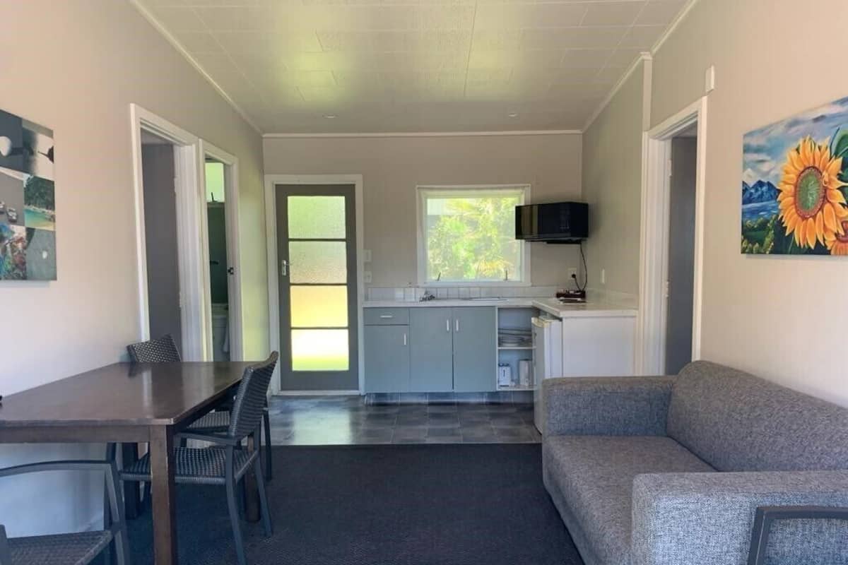 A compact living space with a dining area, kitchenette, and a gray sofa.