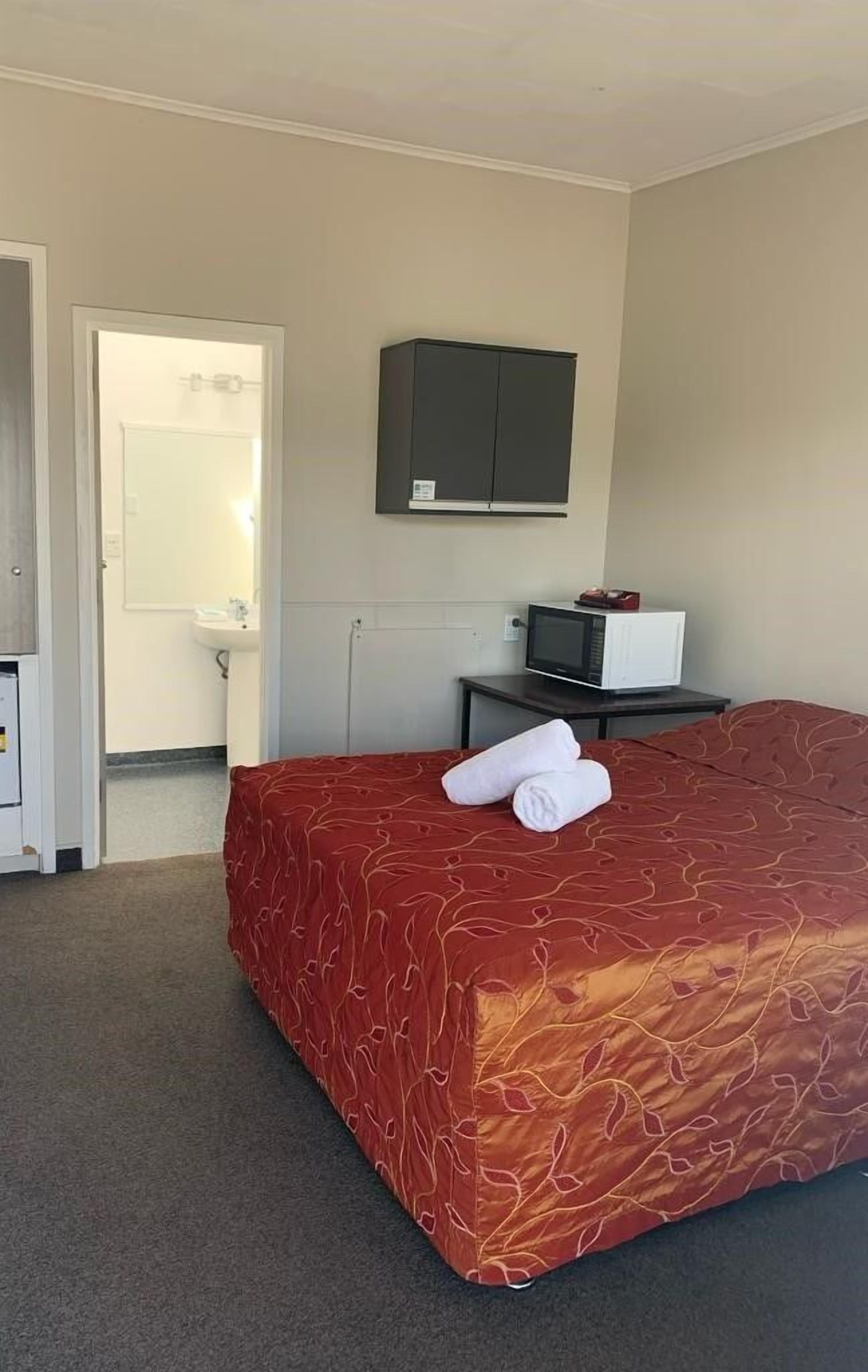 A hotel room with a bed, a desk with a computer, a TV, and a cabinet.