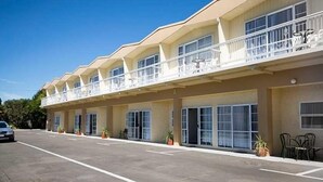 A motel with multiple balconies, large windows, and a parking lot.