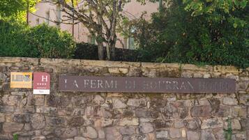 Un muro de piedra con carteles que indican "LIENS RESTAURANT" y "LA FERME DE BOURBAN HOTEL".