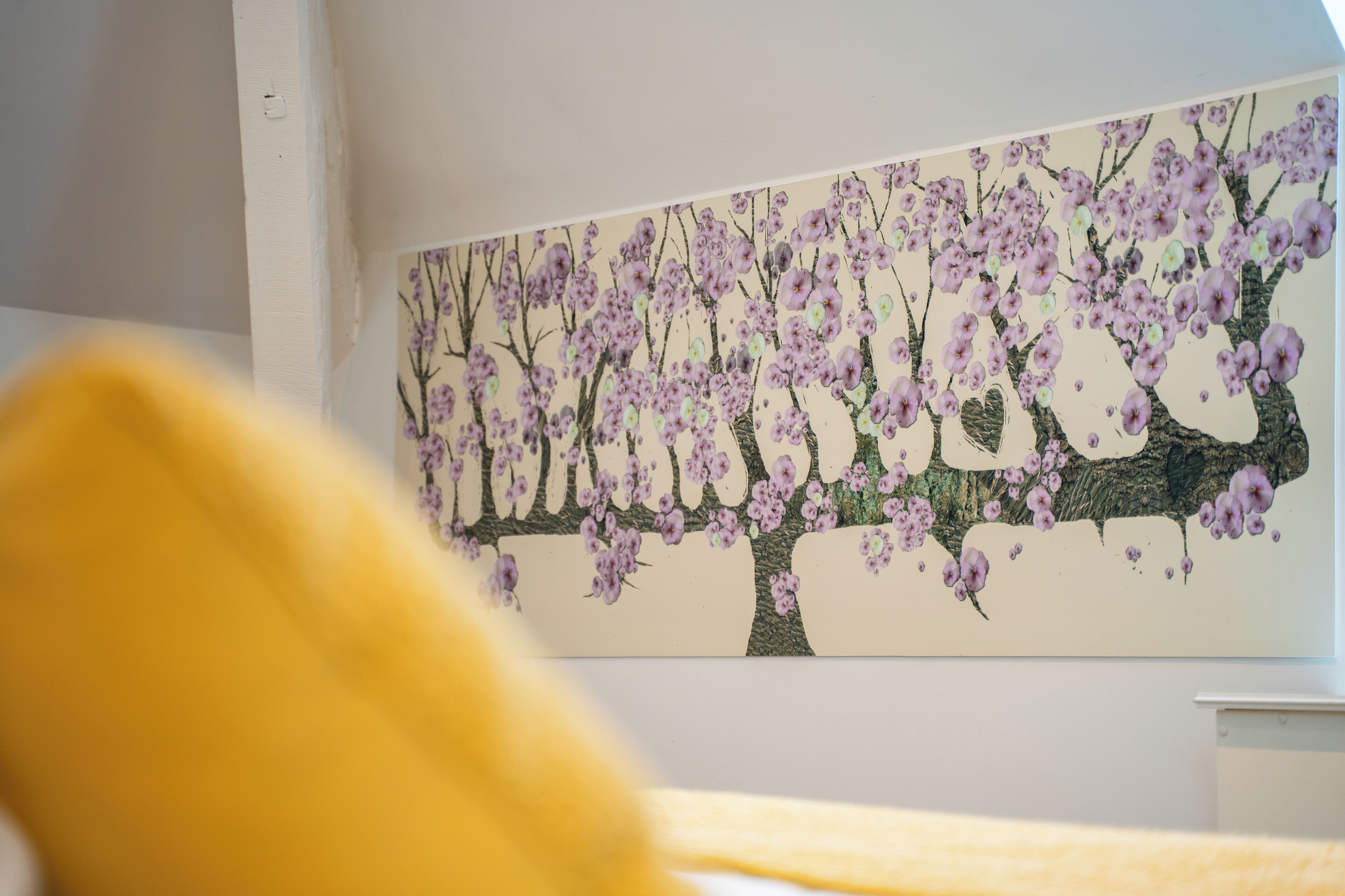 A room with a large painting of cherry blossoms on the wall.