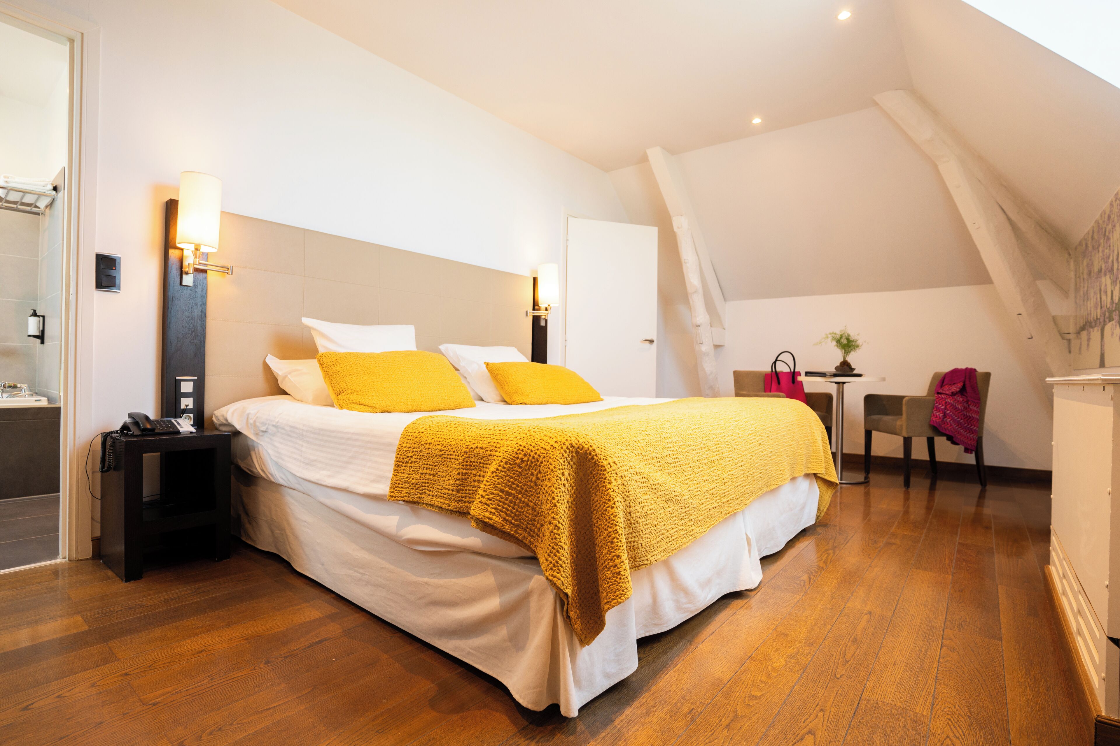 A bedroom with a large bed, a bedside table, a chair, and a desk.
