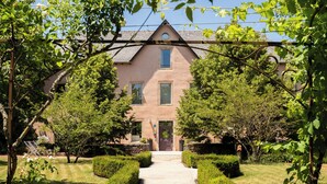 A pathway leading to a building with a symmetrical garden and neatly trimmed hedges.